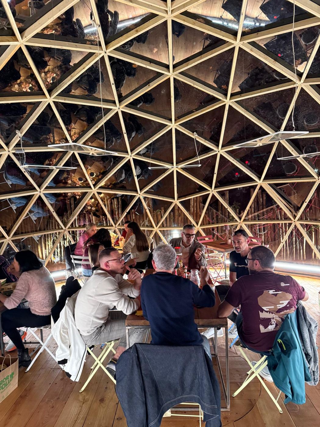 Diners seated inside the dome beneath the exposed timber geodesic lattice